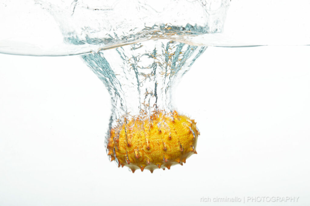 A horned melon splashing down in water