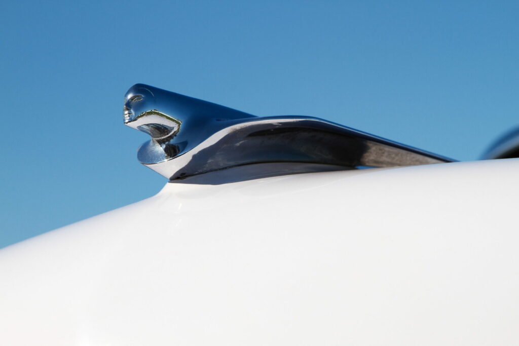 Hood ornament of a classic Cadillac taken from a low angle to imply forward momentum
